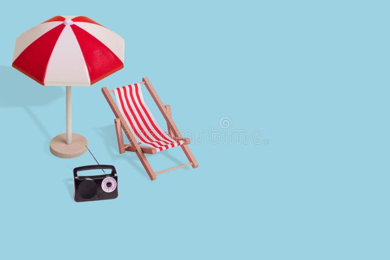 Creative minimal summer idea made of  sun umbrella, deck chair and radio on a light blue background
