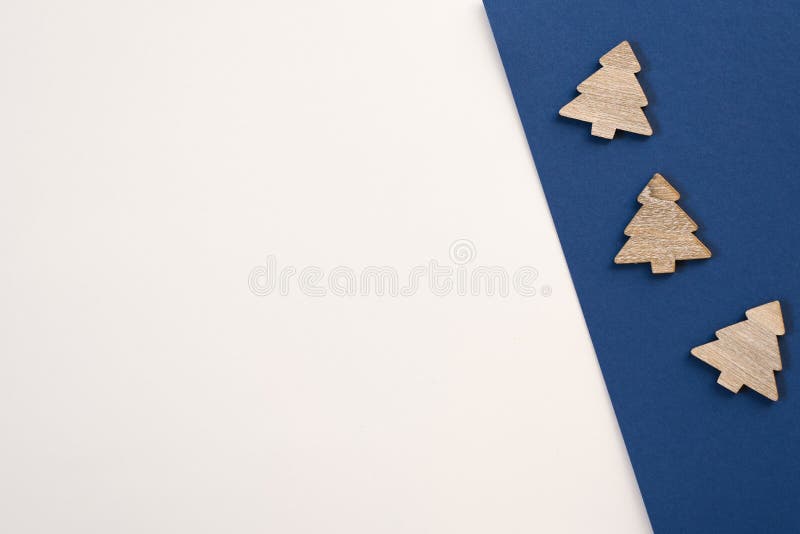 Minimalistic postcard with copy space. Decorative wooden Christmas trees on colored white and blue background royalty free stock photo