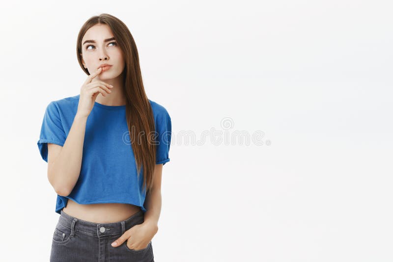 Creative smart and thoughtful attractive european woman in trendy blue cropped top making hmm gesture with finger on