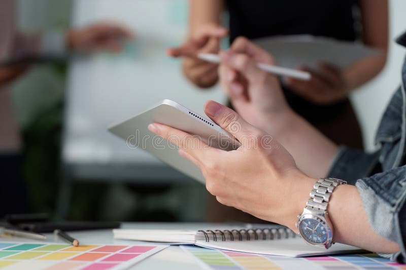 Creative Team Collaboration and UX UI Design. A team member using a tablet while others provide input during a design royalty free stock photos