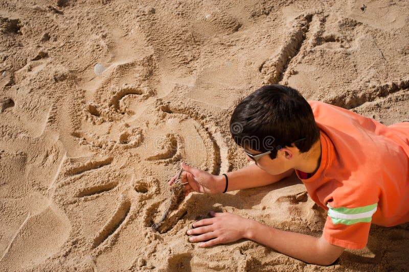 Creative teenager sketching a cartoon on beach sand