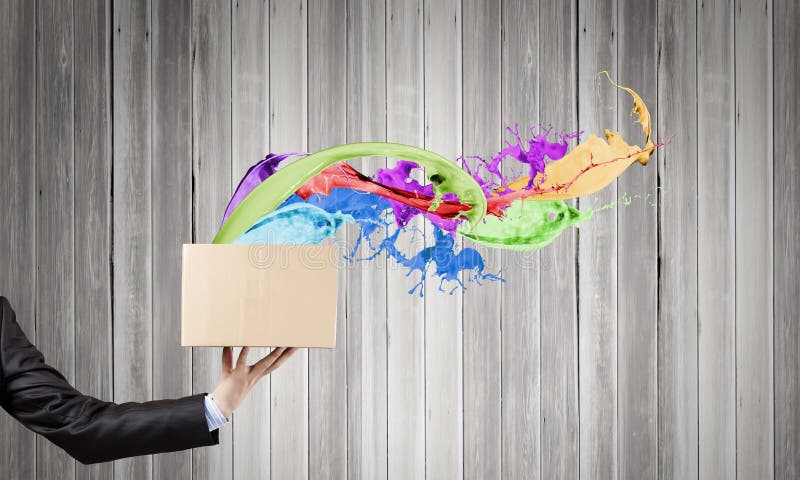 Close up of hand holding carton box with colorful splashes. Close up of hand holding carton box with colorful splashes