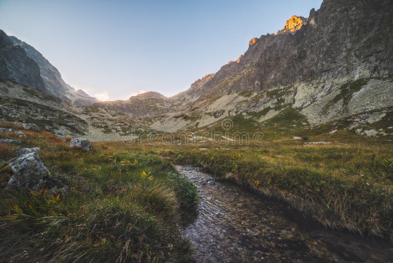 Creek in the Valley under the Mountain Peaks at Sunset