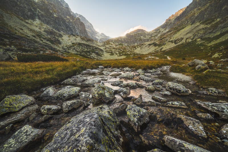 Creek in the Valley under the Mountain Peaks at Sunset