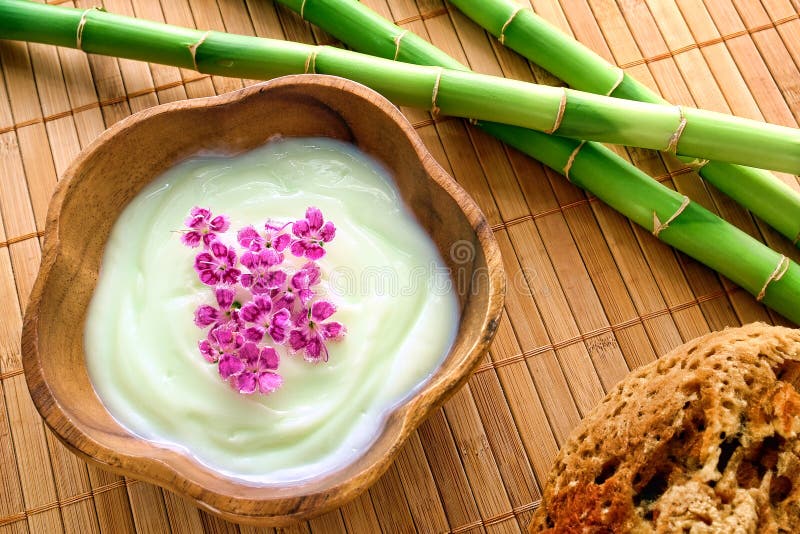 Crema e fiori facciali in ciotola di legno in una stazione termale fotografie stock libere da diritti Crema e fiori facciali in ciotola di legno in una stazione termale fotografie stock libere da diritti