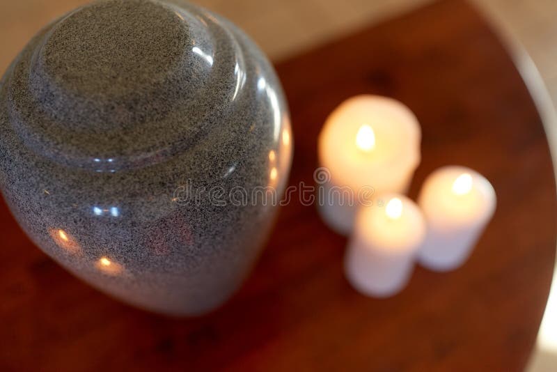 Cremation urn and candles burning on table