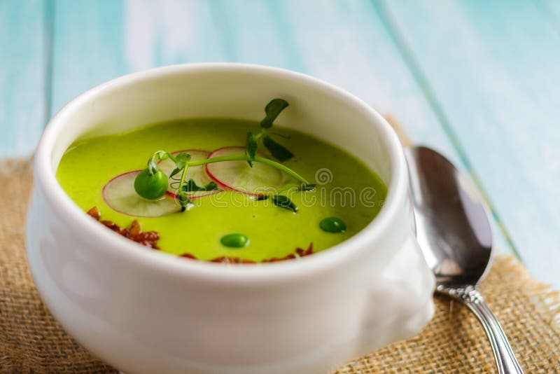 Creme der Suppe der grünen Erbsen in einer weißen Schüssel auf einer Serviette stockfotografie Creme der Suppe der grünen Erbsen in einer weißen Schüssel auf einer Serviette stockfotografie