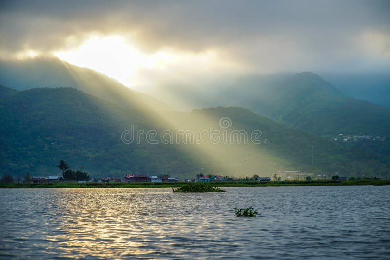 Crepuscular Rays. Sun Shining Through Clouds at Inle Lake in Myanmar Burma stock photo Crepuscular Rays. Sun Shining Through Clouds at Inle Lake in Myanmar Burma stock photo