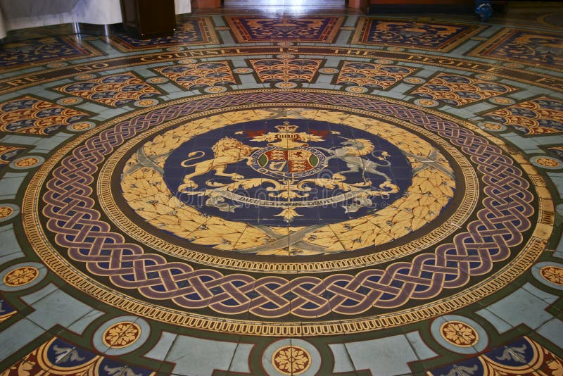Circular royal coat of arms of UK on paved tiled floor inside historic Parliament House of Victoria State, Melbourne, Australia