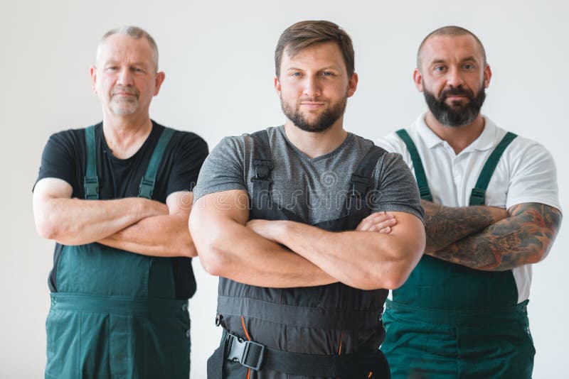 Three professional builder wearing overalls standing in empty interior royalty free stock photography
