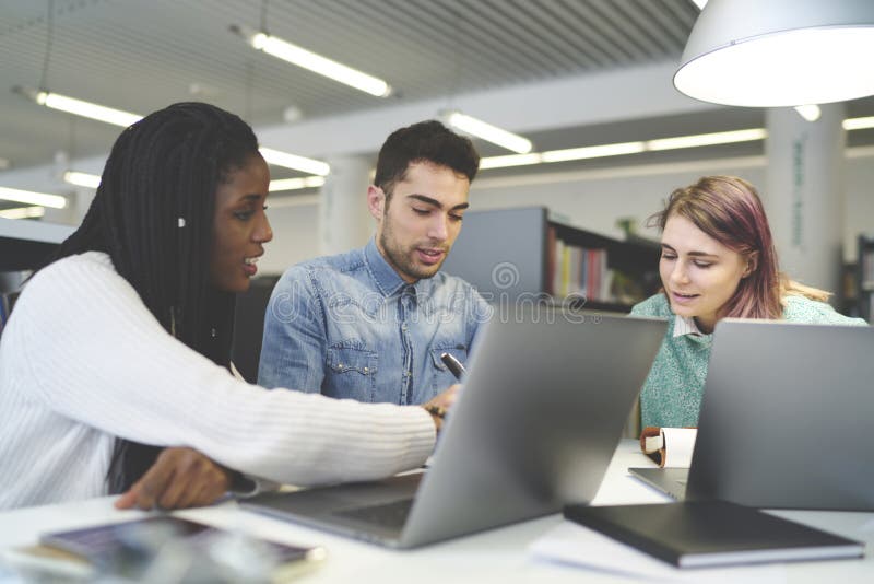 Multiracial group of international students collaborating working on project in university library stock images Multiracial group of international students collaborating working on project in university library stock images