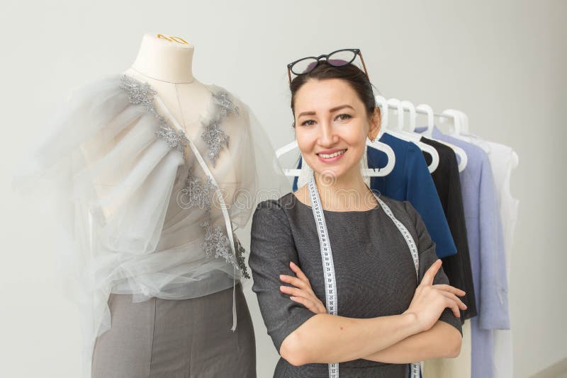 Criador de roupas, designer de moda, alfaiate e conceito de pessoas - moça de moda de mulheres jovens em seu showroom imagens de stock royalty free Criador de roupas, designer de moda, alfaiate e conceito de pessoas - moça de moda de mulheres jovens em seu showroom imagens de stock royalty free
