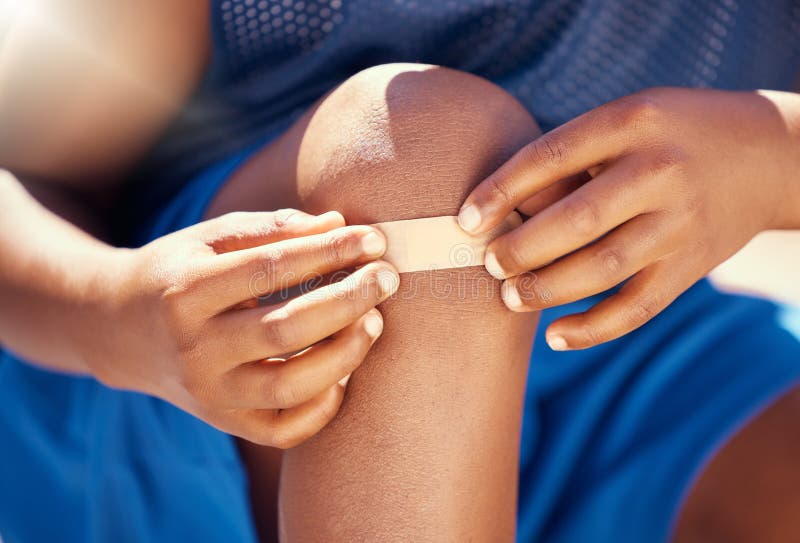 Criança de lesão no joelho de basquete com o pai colocou band-aid