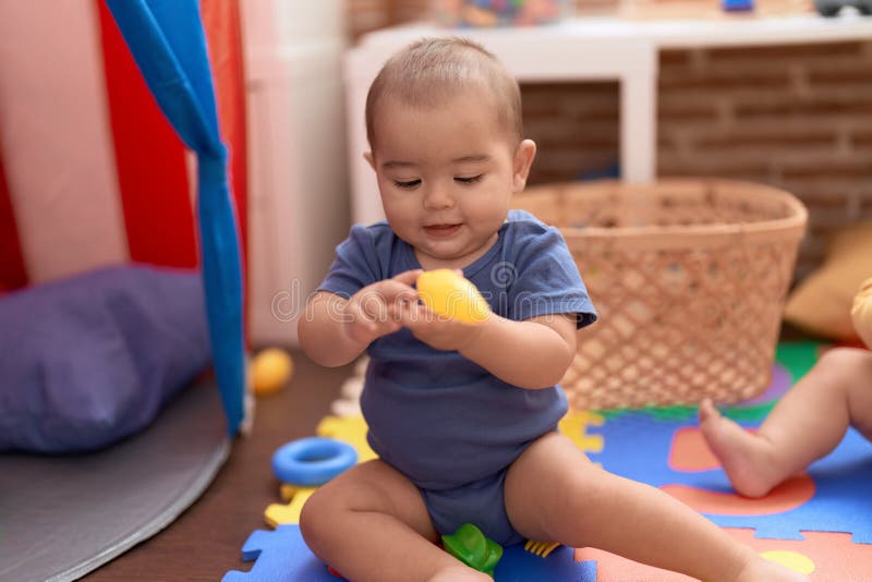 Adorável bebê caucasiano brincando com bolas sentadas no chão no jardim de  infância