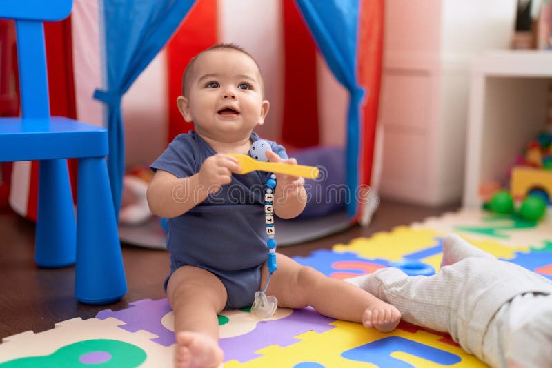 Adorável bebê caucasiano brincando com bolas sentadas no chão no jardim de  infância