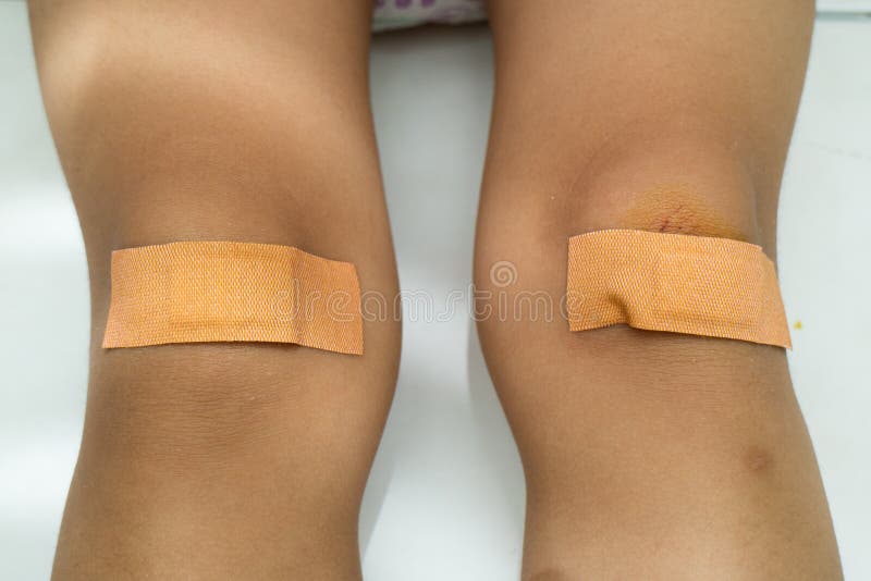 Criança de lesão no joelho de basquete com o pai colocou band-aid