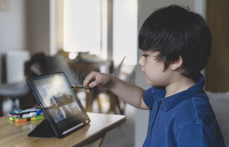 criança jogando jogos online na internet no quarto, retrato de menino  usando tablet digitando ou conversando com amigos de manhã, infância  sentada na cama fazendo lição de casa, criança da escola com