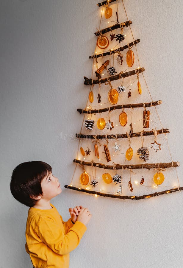Criança Pequena Olhando a árvore De Natal Artesanal Feita De Paus E Materiais Naturais Pendurados Na Parede. Imagem de Stock - Imagem de pinho, canela: 202537143 Criança Pequena Olhando a árvore De Natal Artesanal Feita De Paus E Materiais Naturais Pendurados Na Parede. Imagem de Stock - Imagem de pinho, canela: 202537143