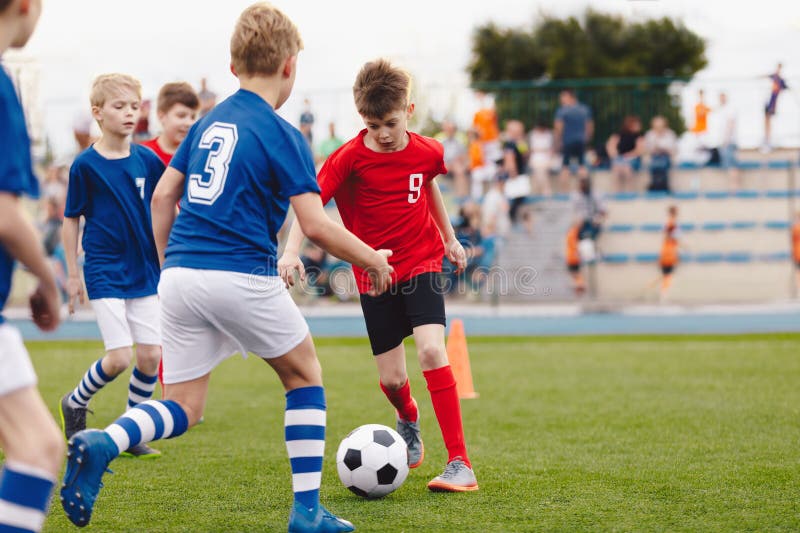 Jogo De Futebol. Crianças Jogando Futebol. Meninos Jovens Chutando Bola De  Futebol No Campo De Esportes. Crianças Jogando Jogo De Torneio De Futebol  No Campo. Juventude Jogo De Futebol Europeu Foto Royalty