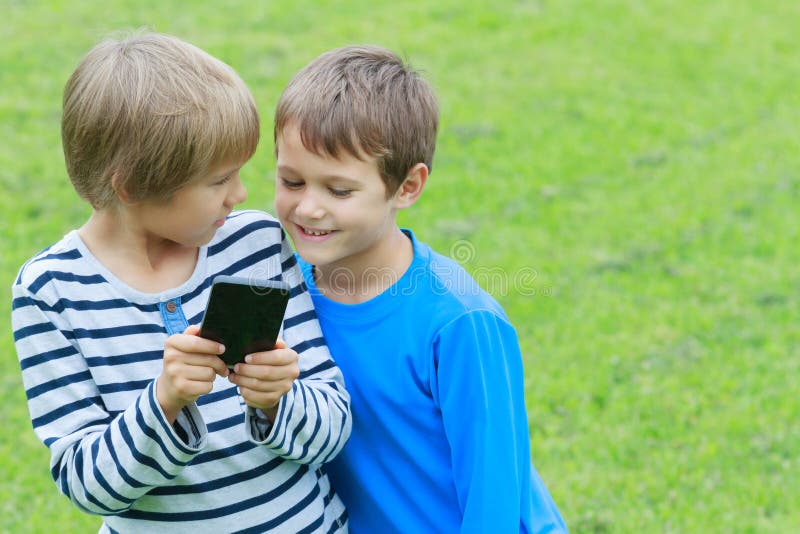 Crianças Com O Telefone Celular Exterior Dois Meninos Que Sorriem