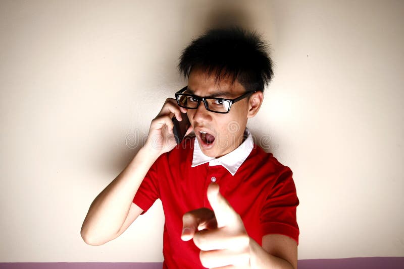 Criança adolescente irritada que fala em um smartphone e que aponta na câmera fotos de stock Criança adolescente irritada que fala em um smartphone e que aponta na câmera fotos de stock
