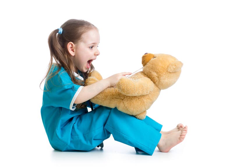 Criança adorável vestida como o doutor que joga com urso de peluche fotos de stock Criança adorável vestida como o doutor que joga com urso de peluche fotos de stock