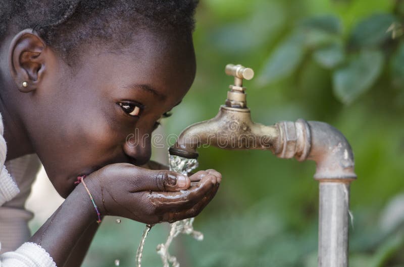 Criança africana bonita que bebe de um símbolo da escassez do água da torneira