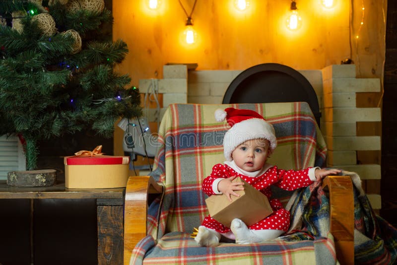Criança com um presente de Natal no fundo de madeira Crianças do Natal A criança pequena bonito está decorando a árvore de Natal imagem de stock Criança com um presente de Natal no fundo de madeira Crianças do Natal A criança pequena bonito está decorando a árvore de Natal imagem de stock