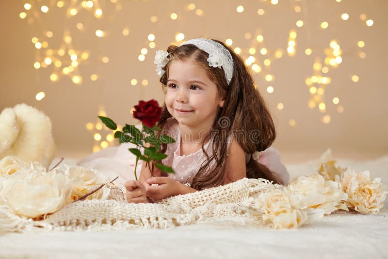 A criança da menina com flor cor-de-rosa está levantando em luzes de Natal, fundo amarelo, vestido cor-de-rosa imagens de stock royalty free A criança da menina com flor cor-de-rosa está levantando em luzes de Natal, fundo amarelo, vestido cor-de-rosa imagens de stock royalty free