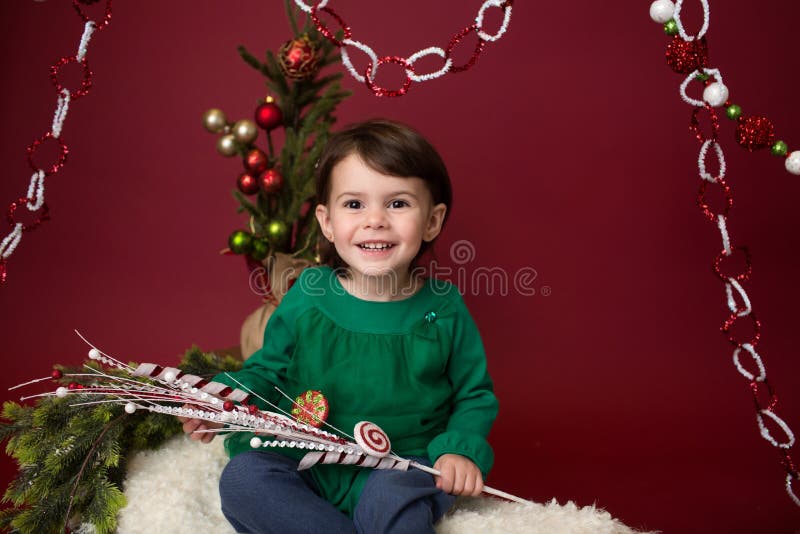 Criança do Natal no trenó contra a árvore de Natal com ornamento fotos de stock