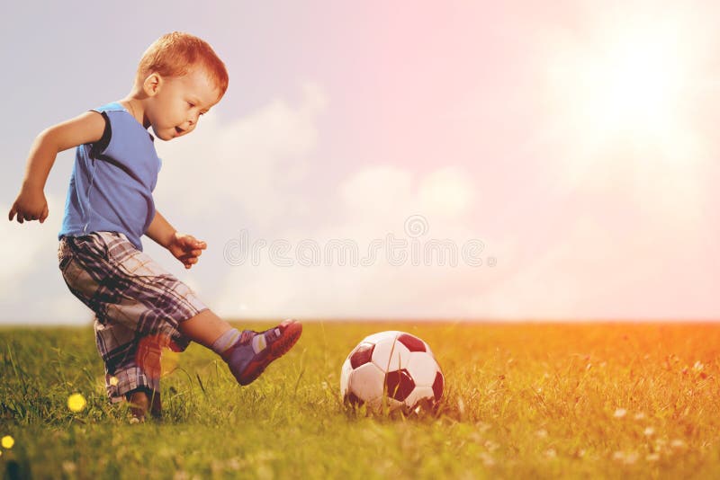 Criança dos esportes Menino que joga o futebol Bebê com a bola no campo de esportes