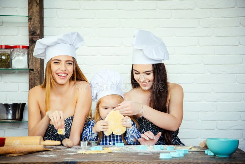 Criança e mulheres que cortam o formulário para a cookie na massa imagem de stock Criança e mulheres que cortam o formulário para a cookie na massa imagem de stock