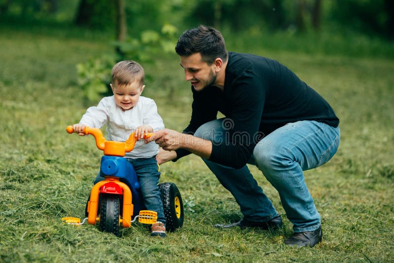 Child on a bicycle get from father first lessons of ride. Child on a bicycle get from father first lessons of ride