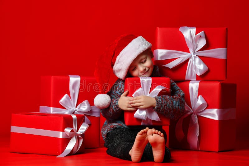 Criança engraçada de sorriso no chapéu vermelho de Santa que mantém o presente do Natal disponivel Conceito do Natal imagens de stock Criança engraçada de sorriso no chapéu vermelho de Santa que mantém o presente do Natal disponivel Conceito do Natal imagens de stock