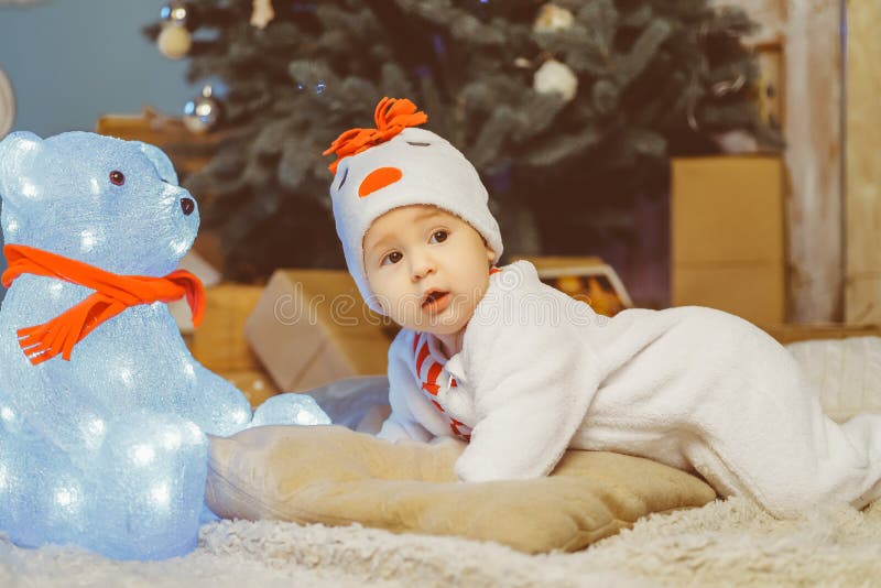 Criança engraçada que encontra-se na cama ao lado do urso de peluche foto de stock Criança engraçada que encontra-se na cama ao lado do urso de peluche foto de stock