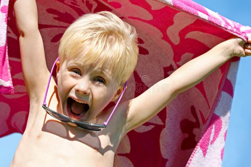 Criança entusiasmado na toalha de praia no dia de verão