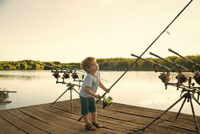 Criança feliz que tem o divertimento Criança dobrando com a vara de pesca no cais de madeira foto de stock Criança feliz que tem o divertimento Criança dobrando com a vara de pesca no cais de madeira foto de stock