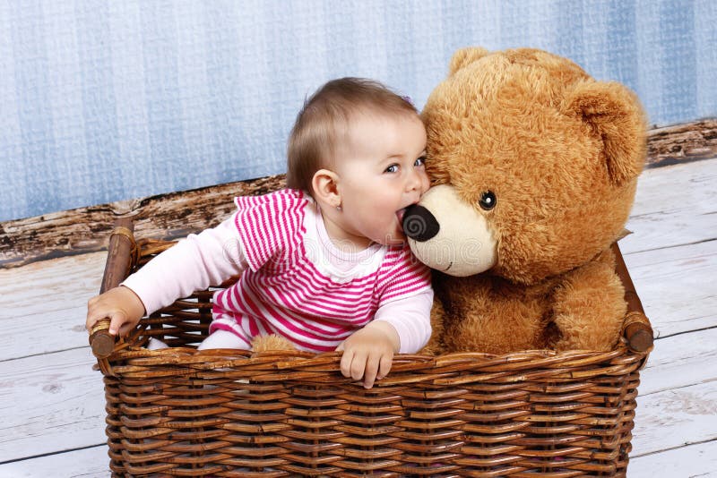 Criança pequena com o urso de peluche que senta-se na cesta fotos de stock Criança pequena com o urso de peluche que senta-se na cesta fotos de stock