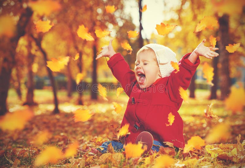 Criança pequena feliz, bebê que ri e que joga no outono