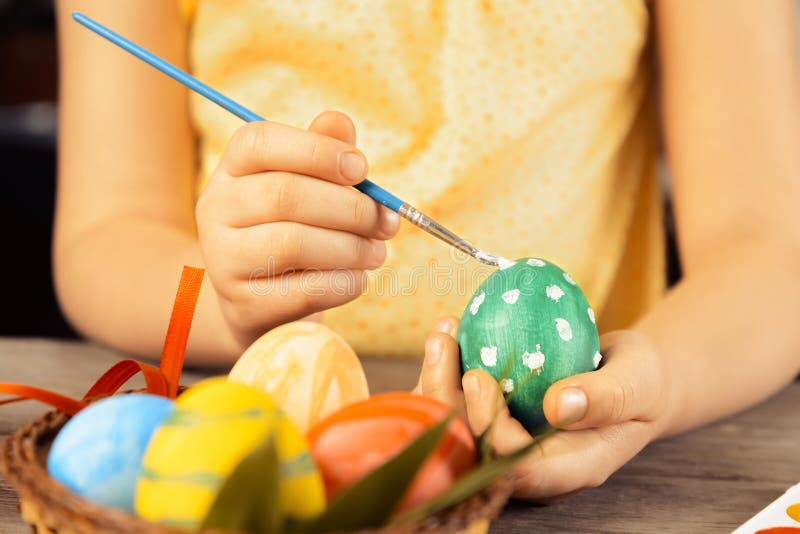 A criança pinta o ovo bonito para a Páscoa