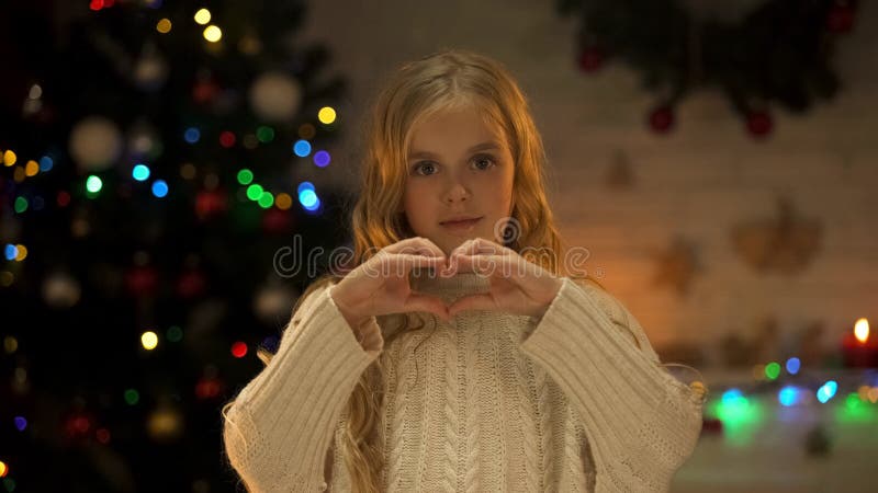 Criança que faz o coração com as mãos que olham à câmera, ao amor e à caridade no Natal foto de stock royalty free Criança que faz o coração com as mãos que olham à câmera, ao amor e à caridade no Natal foto de stock royalty free