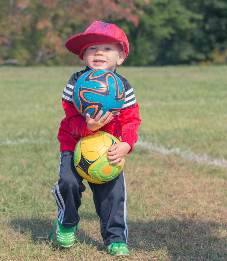 Criança que guarda bolas de futebol fotos de stock Criança que guarda bolas de futebol fotos de stock