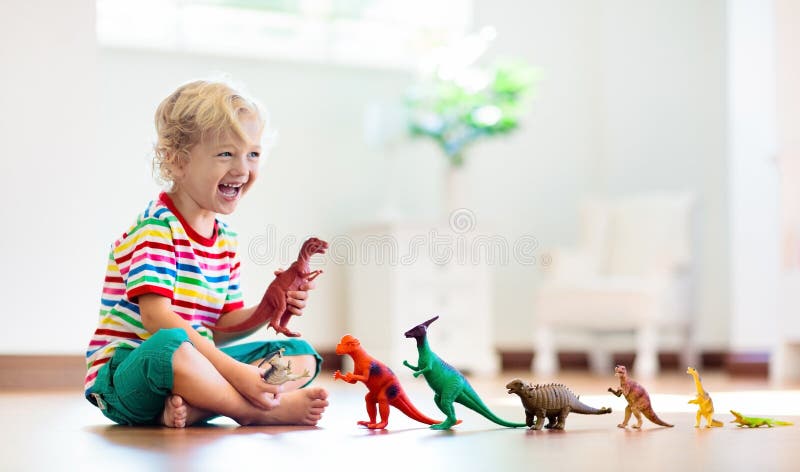 Criança que joga com dinossauros do brinquedo Brinquedos das crianças foto de stock Criança que joga com dinossauros do brinquedo Brinquedos das crianças foto de stock