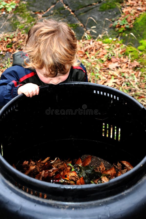 Criança que olha no escaninho de adubo foto de stock Criança que olha no escaninho de adubo foto de stock