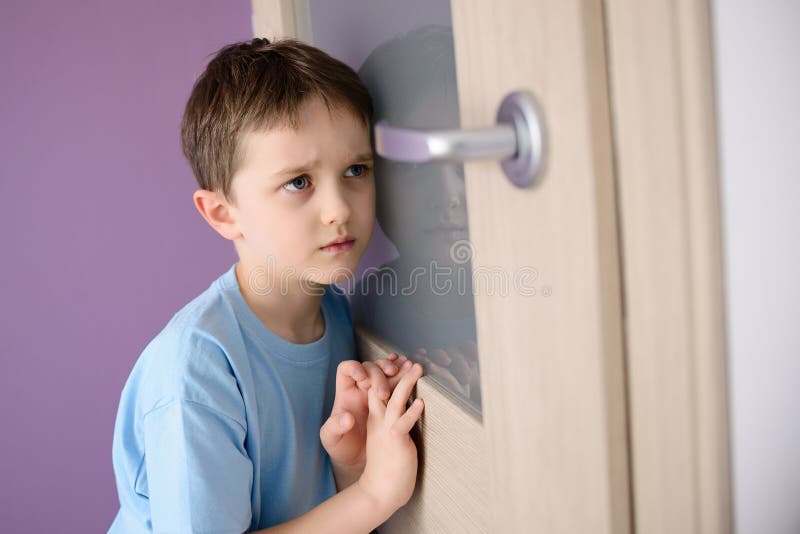 Criança triste, amedrontada que escuta um pai que fala através da porta