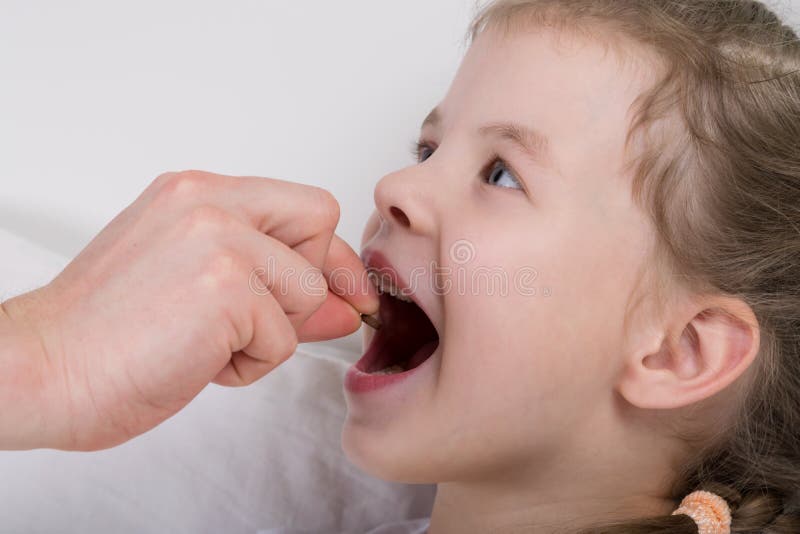 A criança, uma menina, pôs a tabuleta diretamente na boca