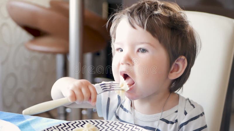 A criança à mesa comendo comida quente. criança do café da manhã não refrigerada