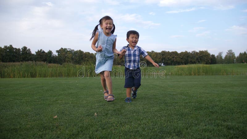 Crianças asiáticas alegres que correm junto no parque