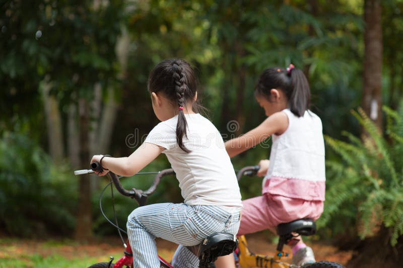Crianças asiáticas ativas que montam a bicicleta exterior imagem de stock Crianças asiáticas ativas que montam a bicicleta exterior imagem de stock