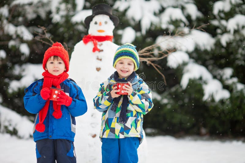 Crianças bonitas felizes, irmãos, boneco de neve de construção no jardim fotografia de stock royalty free Crianças bonitas felizes, irmãos, boneco de neve de construção no jardim fotografia de stock royalty free